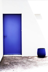 Porte bleue et pot bleu sur mur blanc