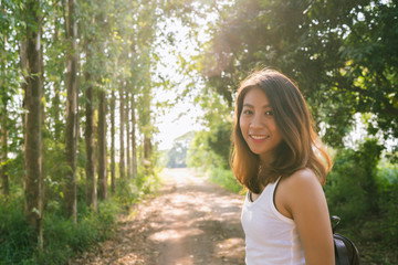 Happy young Asian woman traveler with backpack walking in forest. Hiker Asian woman with backpack...
