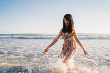 Young Asian woman walking on beach. Beautiful female happy relax walking on beach near sea when sunset in evening. Lifestyle women travel on beach concept.
