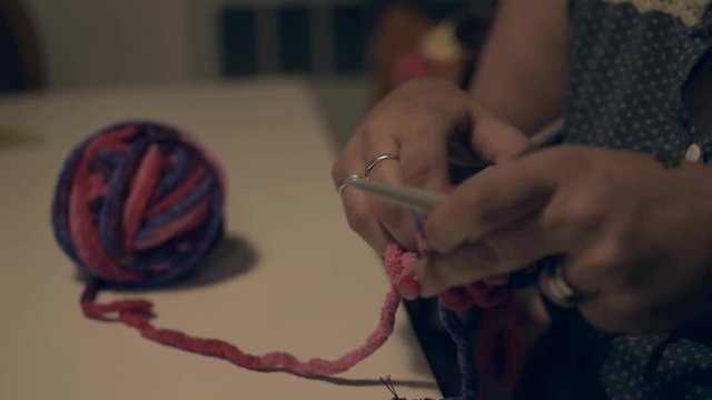 Young woman knitting with stitches a colorful craft in a cozy autumn day, closeup.
