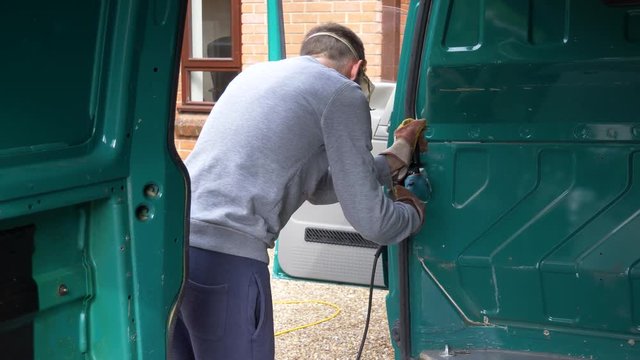 Person cutting out van bulkhead with angle grinder