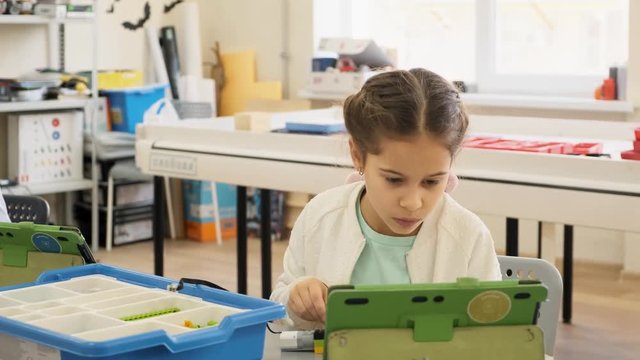 Little girl shows on her ipad the nessesary plastic construction for the educational lesson slow motion