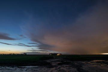 April shower over the wet dutch countryside against the twilight sky