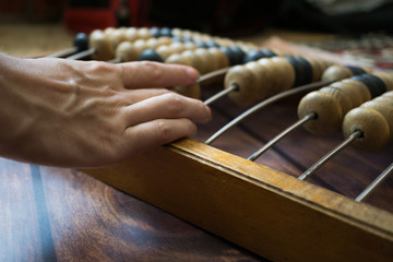Old vintage abacus and hand of girl using it on wooden background