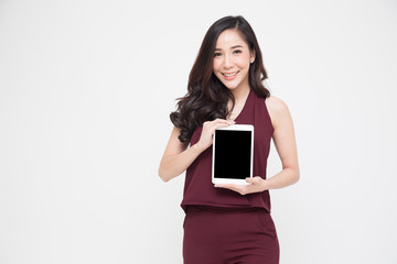 Fototapeta premium Portrait of a cheerful beautiful girl wearing red dress and showing or presenting tablet application isolated over white background, Asian Thai model
