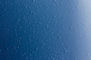Clear water drops on a blue surface. Abstract background.