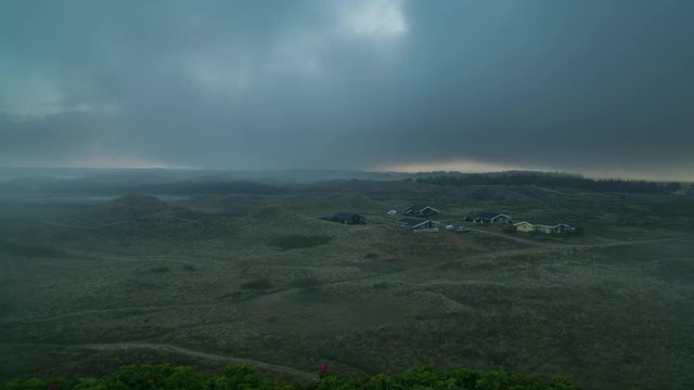 Landscape timelapse of moving fog in the dunes of Hvide Sande in Denmark right after sunrise