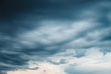 Dramatic cloudscape. Sunny light through dark heavy thunderstorm clouds before rain. Overcast rainy bad weather. Storm warning. Natural gray background of cumulonimbus. Sunlight in stormy cloudy sky.