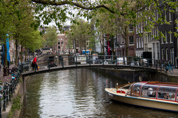 Fototapeta na wymiar Tourist Canal Boats in the Herengracht (Gentlemen's Canal) with its large historic houses in the city center of Amsterdam