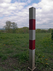 Weiß und roter Metallpfosten als Absperrung damit kein Fahrzeug auf die Wiese fährt.