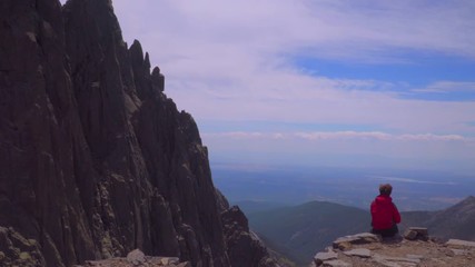 Woman observes the landscape from the rocky mountain