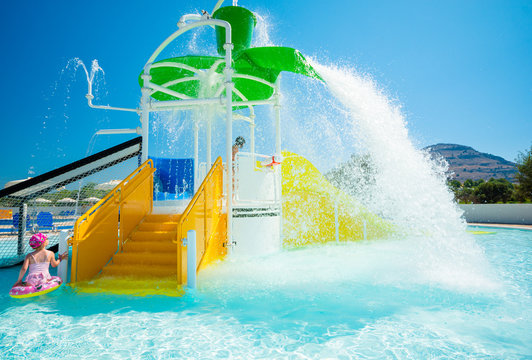Children's water playgrounds and flip-flops with flowing, falling and splashing water. Moment pouring the bucket with water. In the background azure sky.