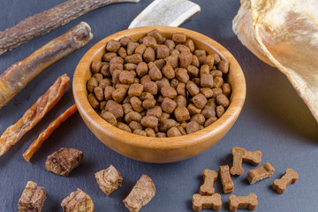 different dog food and snack, chicken filet, antlers, lung, ear on black background