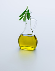 Carafe with olive oil and olive twig from olive tree. Isolated on white