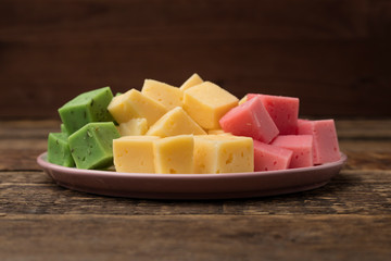 Set of multicolored cheese on a plate, wooden background. Wine Snack