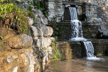 A three-level waterfall flowing among the stone walls of the park.