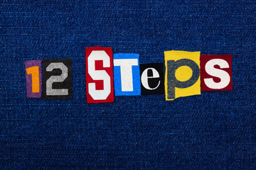 12 STEPS word text collage, multi colored fabric on blue denim, addiction and recovery concept,...