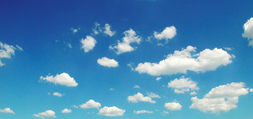 Fluffy clouds in the blue sky. Wide photo.