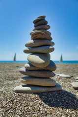 Stones pyramid on pebble beach symbolizing stability, zen, harmony, balance. Shallow depth of field.
