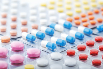 Heap of medical pills in white, blue and other colors. Pills in plastic package. Concept of healthcare and medicine.