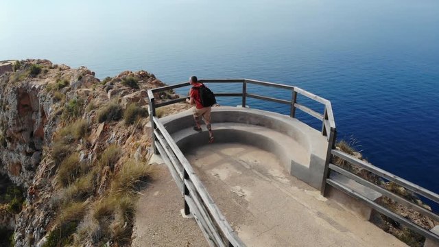 Ein Wanderer am spanischen Berg Cabo Tinoso nahe Cartagena. Eine Plattform bietet eine fantastische Aussicht auf das Mittelmeer. Ein Geländer aus Holz sichern den Wanderer. Luftaufnahme 4k.