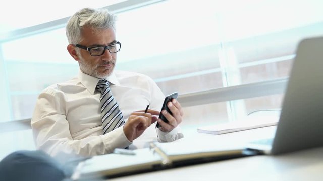 Relaxed businessman on cellphone in office