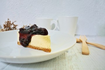 Blueberry cheesecake in a white plate on a vintage white wooden table.
