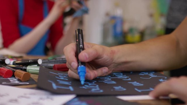 Barista learning how to write on blackboard with a chalk pen