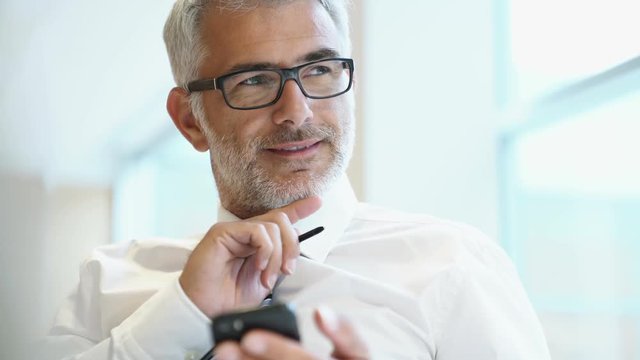 Close Up Of Mature Businessman On Cellphone In Office