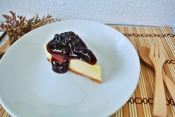 Blueberry cheesecake in a white plate on a vintage white wooden table.