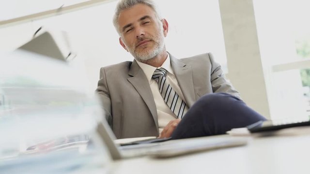 Relaxed corporate businessman sitting at desk