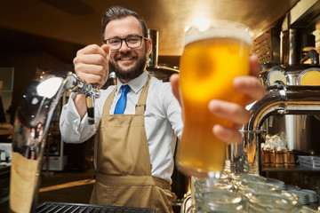 Lager beer glass with foam in bartender's hand close up.