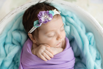 A sleeping newborn baby on a  blue and   purple background.  