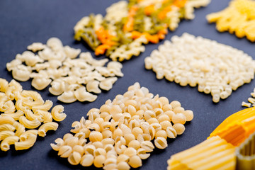 different varieties of pasta on a black background, lined with mosaics