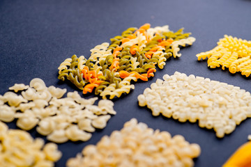 different varieties of pasta on a black background, lined with mosaics