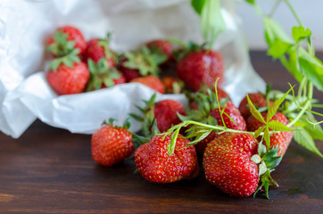 Summer harvest of juicy ripe tasty strawberries with green twig on dark table