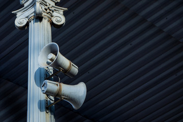 Two horn load speaker on antique column metal frame under roofing. Industrial or transport...