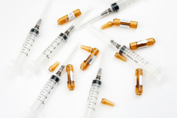 Plastic syringes with used ampoules on a white background, close-up shot, top view