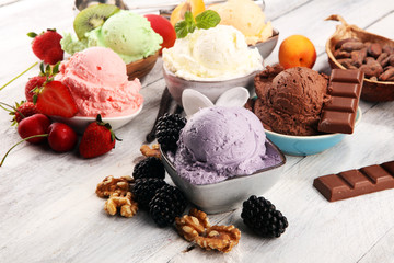 ice cream scoops of different colors and flavours with berries, nuts and fruits decoration on white...