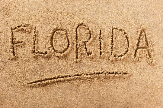 Florida word written in sand on a sunny summer beach holiday vacation travel destination sign writing message photo