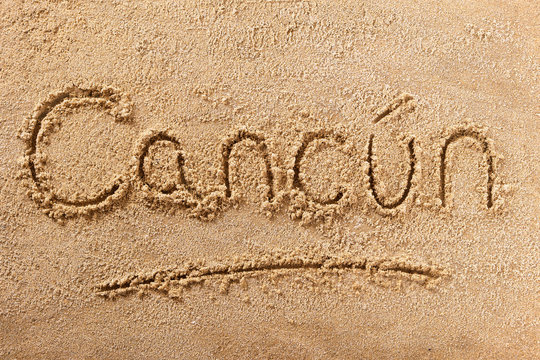 Cancun word written in sand on a sunny mexico mexican summer beach holiday vacation travel destination sign writing message photo