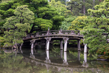 Beautiful scenery at the Kyoto Imperial Palace, with a pond and bridges. On a rainy day, droplets are visible in the air.