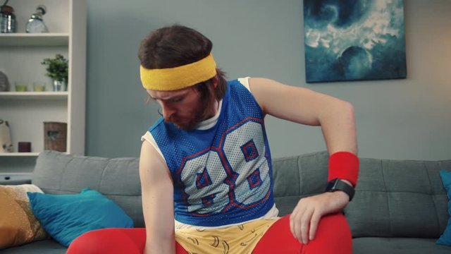 Motivated strong bearded guy in retro outfit training with little dumbbells at home. Portrait of handsome weak man exercising for the firt time.