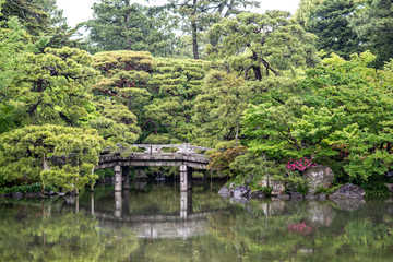 Fototapeta na wymiar Beautiful scenery at the Kyoto Imperial Palace. View of the Oikeniwa gardens, with a pond and bridges. On a rainy day, droplets are visible in the air.