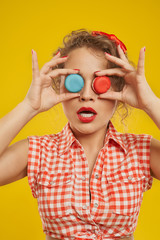 Playful girl holding colorful macarons doing binoculars.