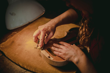 Hands of the luthier working on the violin © Riccardo Russo
