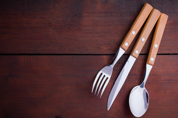 Rustic set of cutlery knife, spoon, fork. Dining set with wooden handles. Wooden background. Copy...