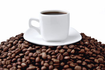 white cup of coffee on a white saucer stands on a hill of coffee beans on a white background