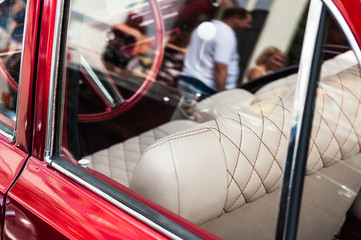 view of the interior of the car, a beautiful line of leather interior and the seat back. cream leather, bright red purple color of the car body. car retropectively. the reflection in the glass.