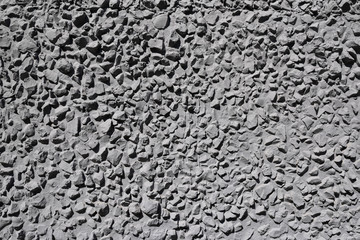 Textured concrete wall with gray, sharp stones.